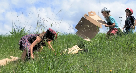 kids playng with cardboard boxes on a hill